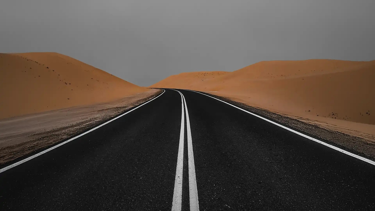 Highway cutting through desert sand dunes on the road from Saudi Arabia to Doha