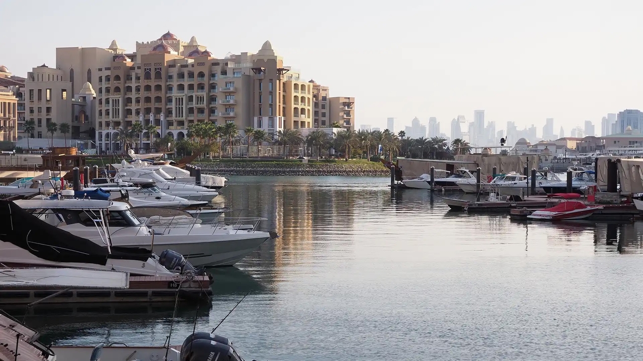 Luxury yachts moored at The Pearl-Qatar marina with the city skyline in the distance.
