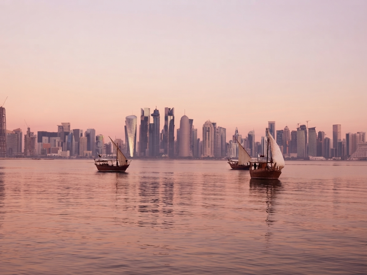 Traditional dhow boats on Doha Bay at sunset with the city skyline in the background