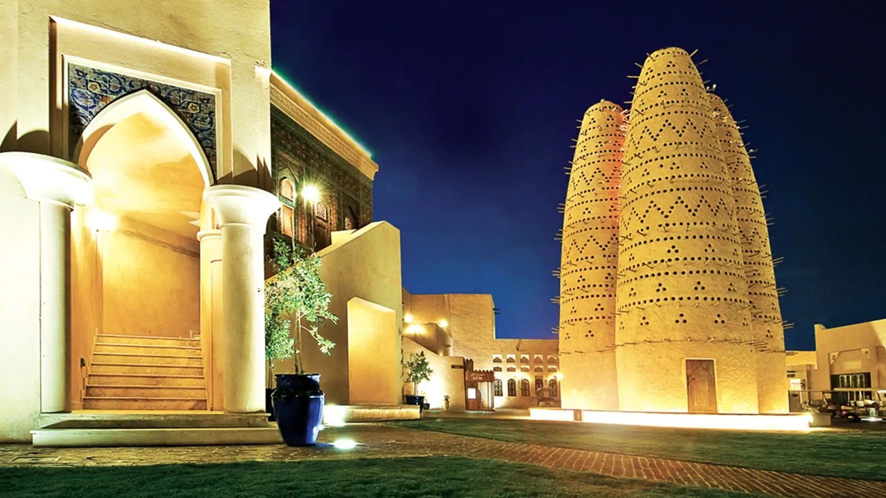 Traditional pigeon towers brightly lit at night inside Katara Cultural Village in Doha.