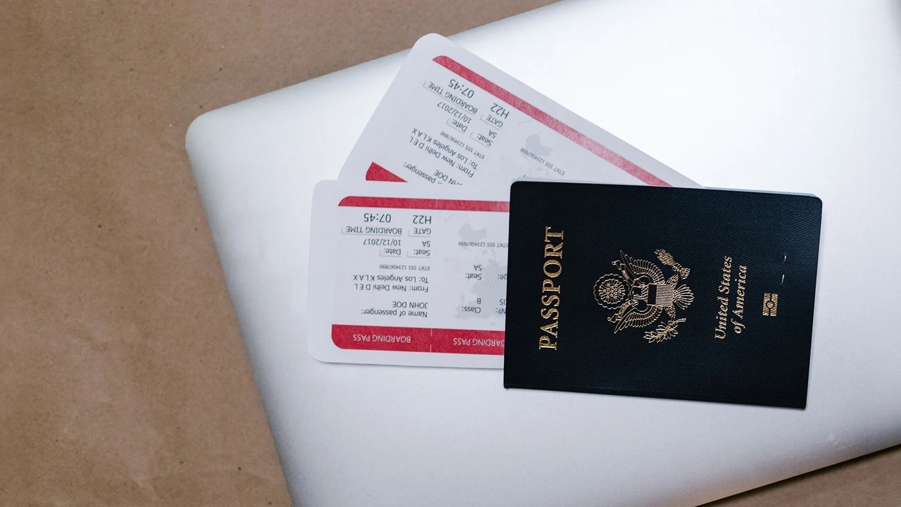 A US passport resting on two boarding passes over a silver laptop.