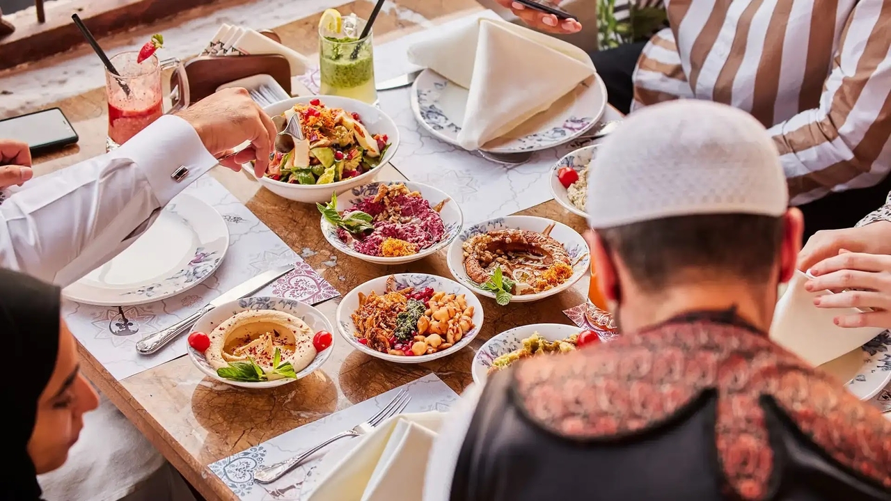 A traditional Qatari meal featuring various mezze dishes like hummus and salads shared at a table.