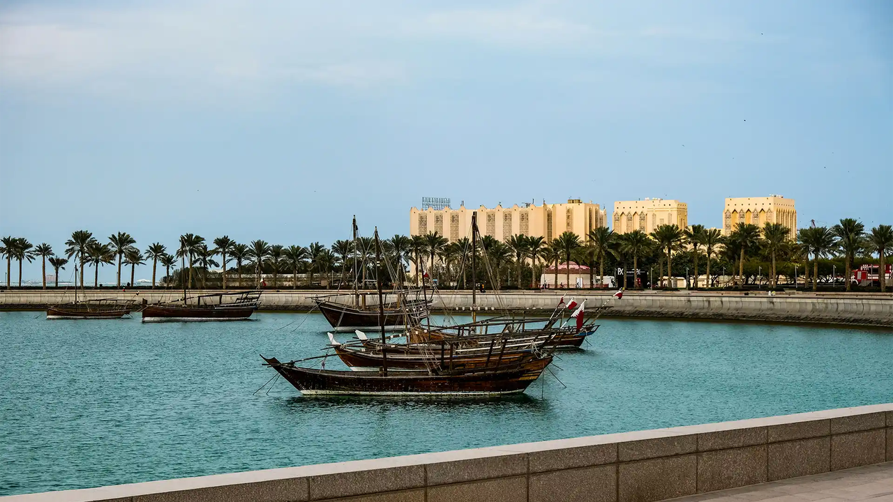 Traditional wooden dhows moored along Doha's palm-lined Corniche waterfront