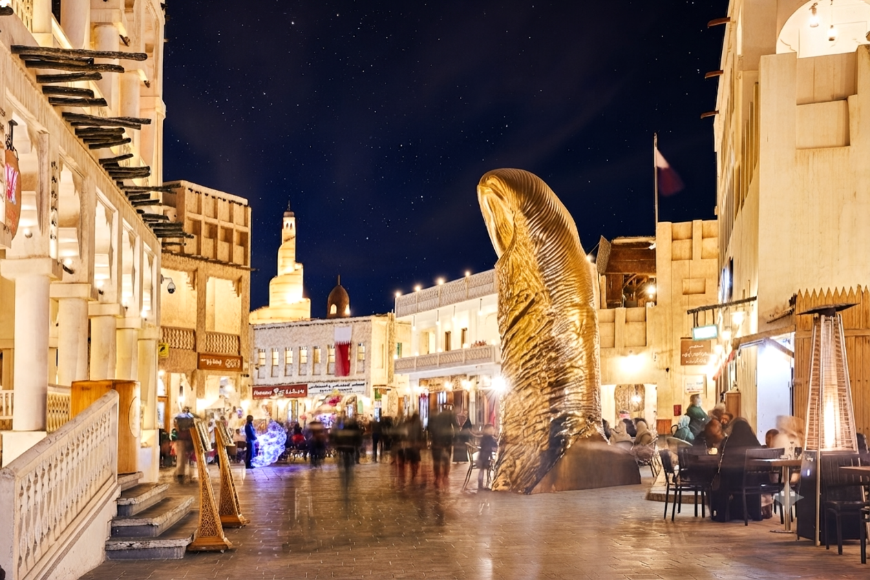 Souq Waqif market at night in Doha, with the golden falcon statue and traditional architecture