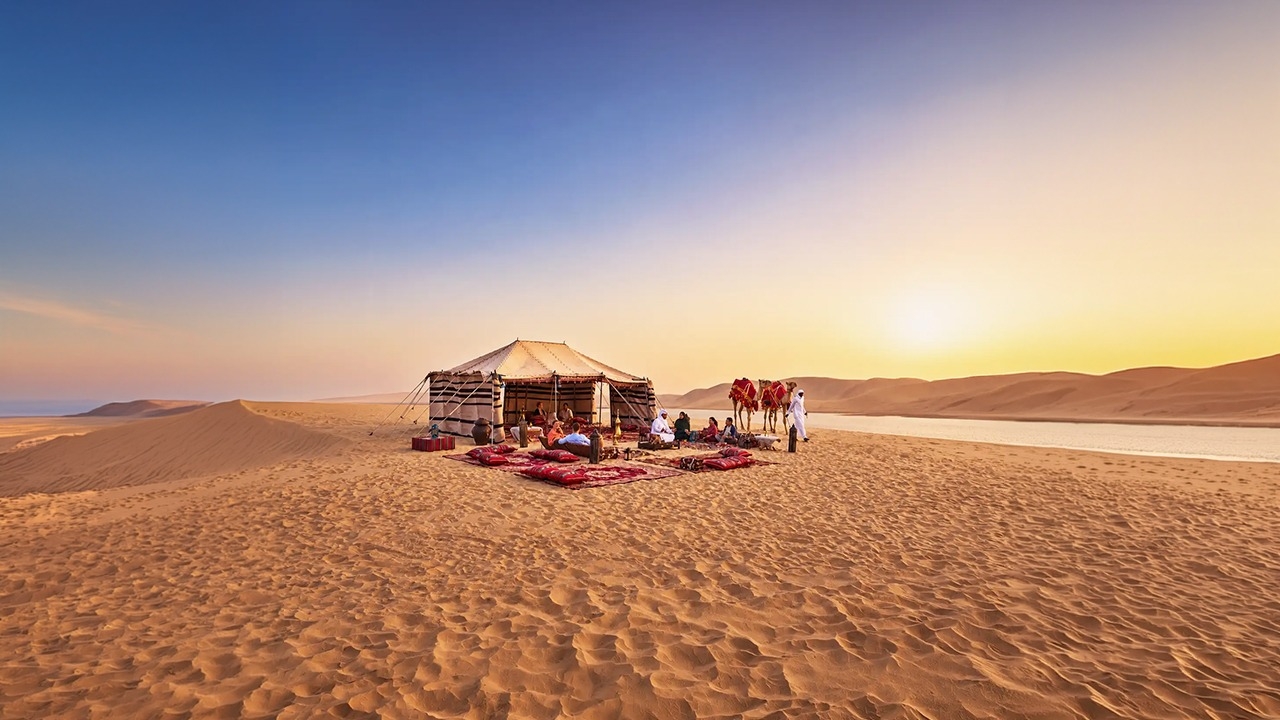Guests relaxing at a traditional Bedouin camp with red rugs, cushions, and camels on the golden sand dunes during a desert safari in Doha, Qatar
