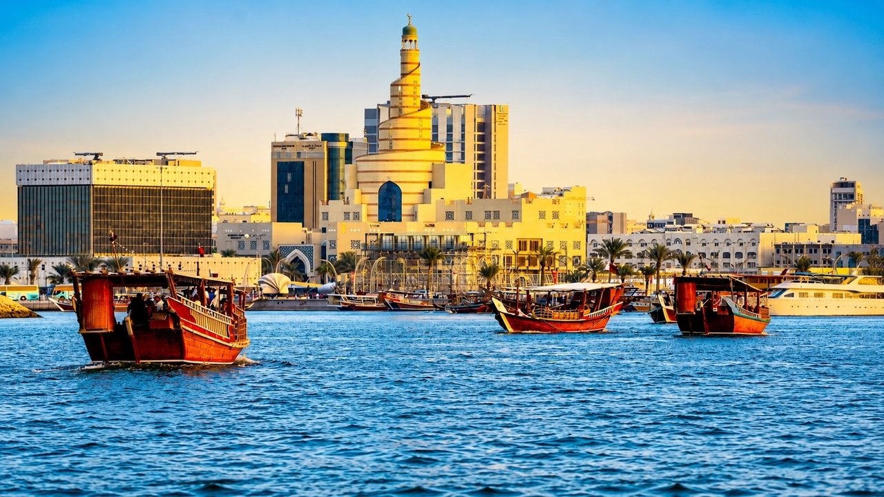 Traditional dhow boats sailing past the Doha skyline with the Fanar Islamic Cultural Center in the background 
