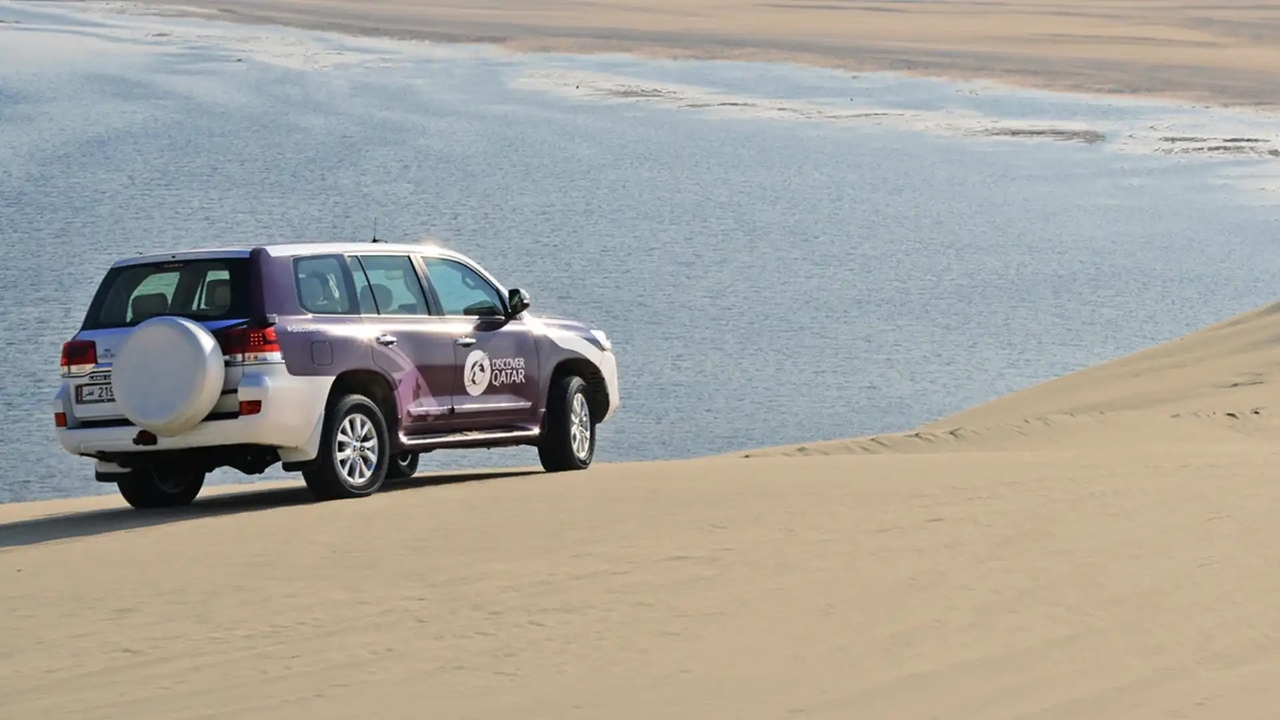4x4 vehicle on Qatar desert dunes overlooking the coast