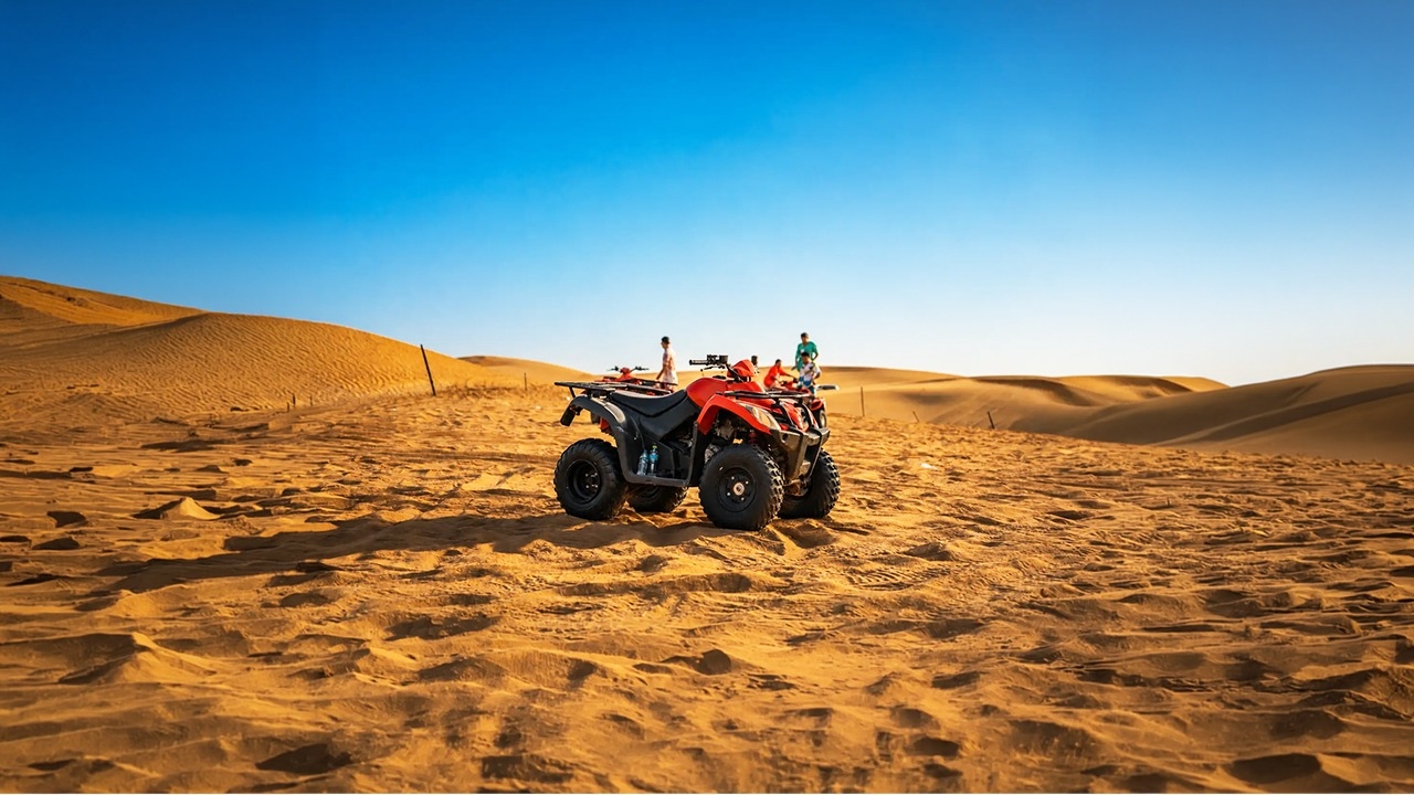An orange and black quad bike parked on a rolling sand dune during a desert safari. In the blurry background, other tourists stand near additional ATVs under a hazy, sand-colored sky.