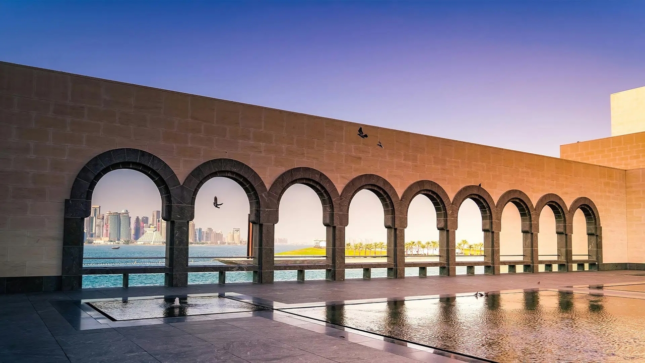 Stone arches at the Museum of Islamic Art terrace framing the sea and West Bay skyline.