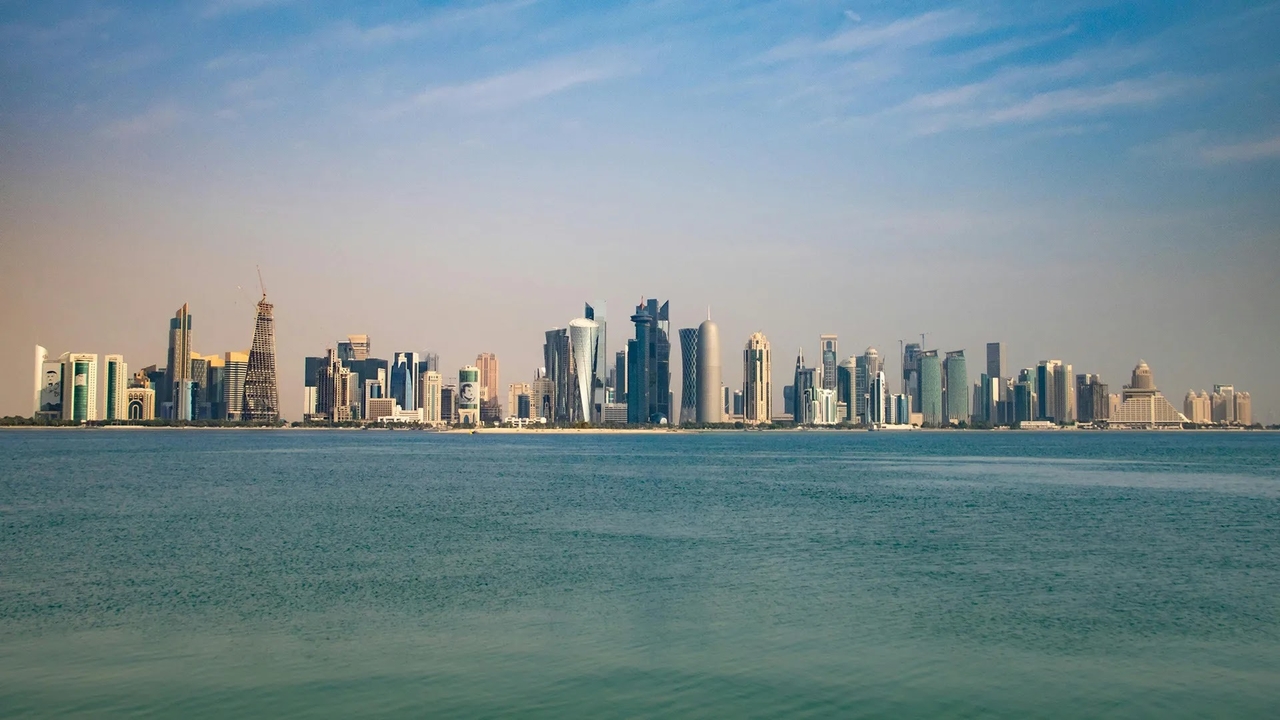 The modern high-rise skyline of the Doha Corniche viewed across the blue bay.