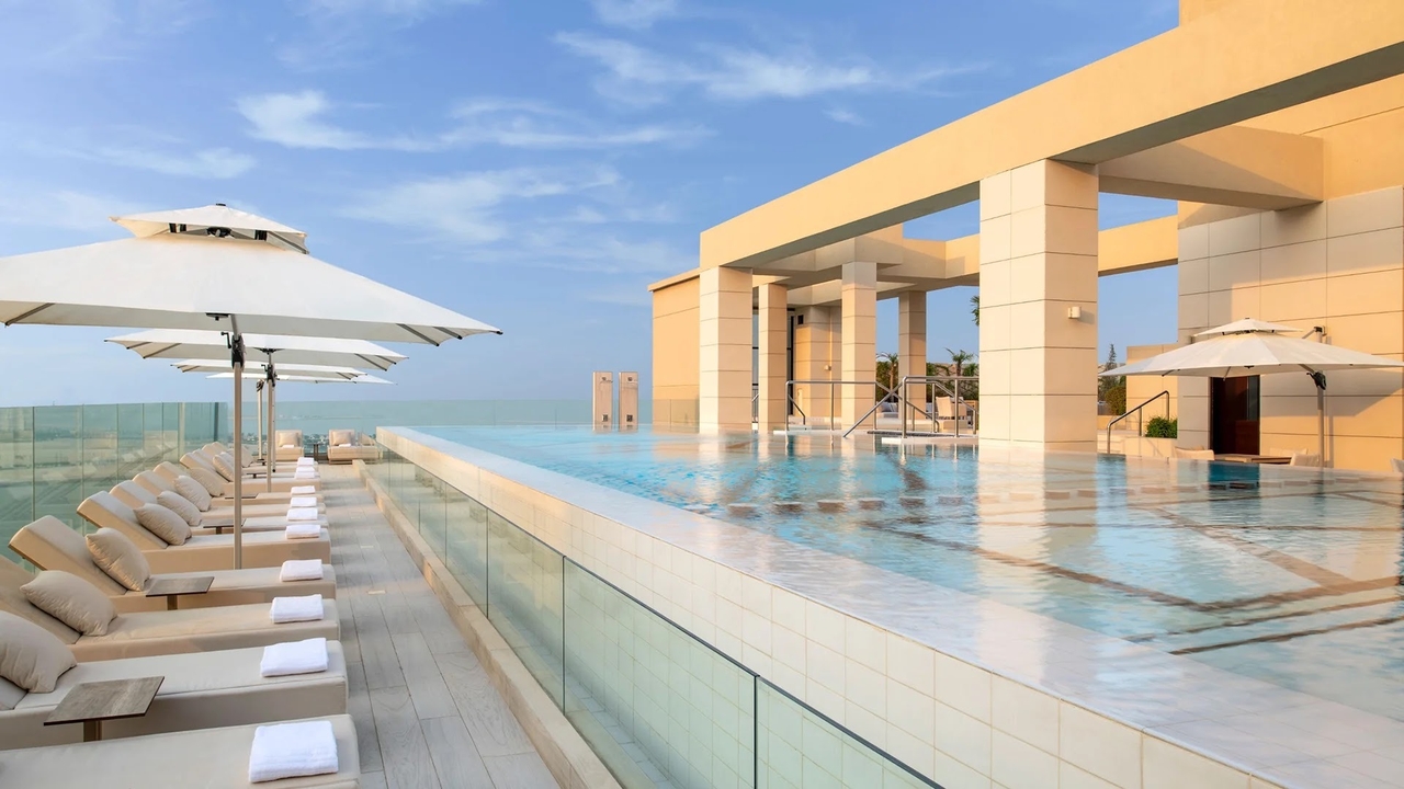Rooftop infinity pool with loungers overlooking Doha's West Bay skyline