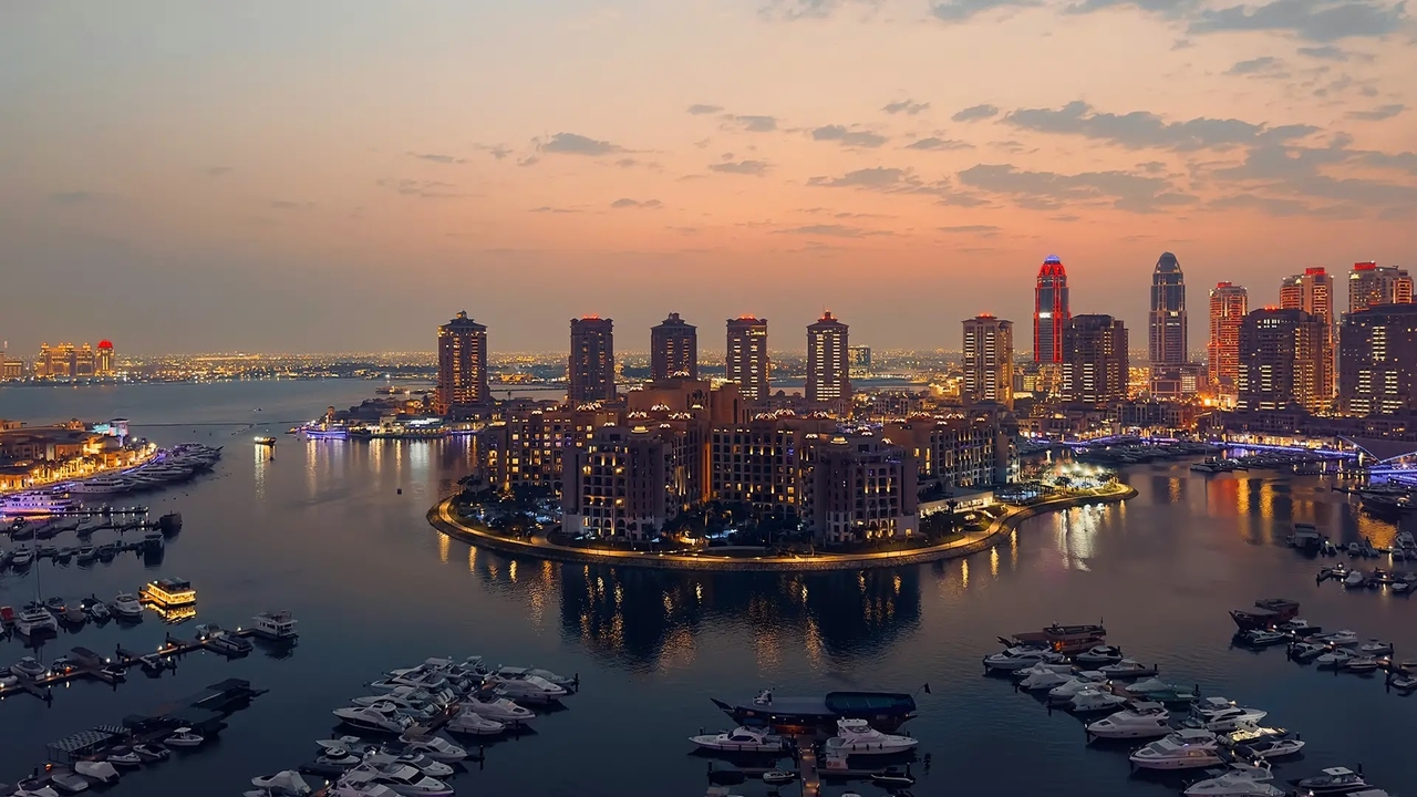 Glowing sunset aerial view of luxury yachts docked at The Pearl marina. 