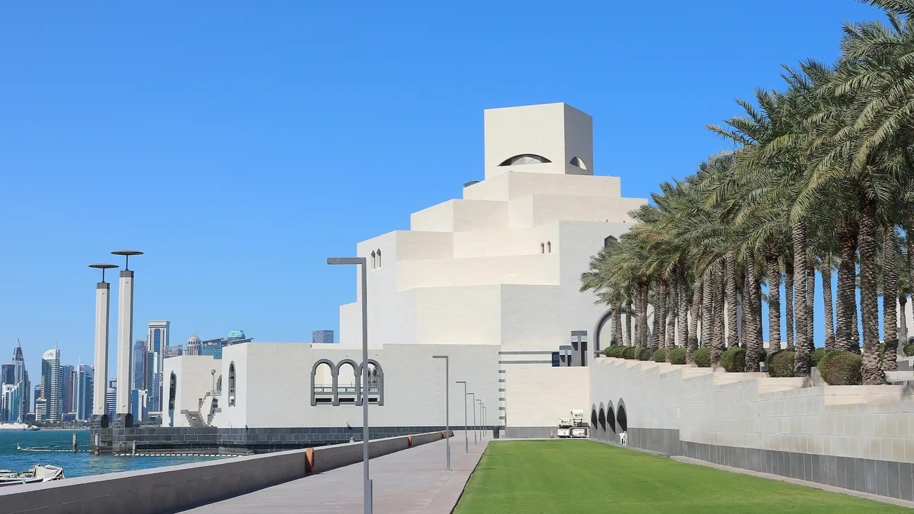 Geometric exterior of the Museum of Islamic Art in Doha against a clear blue sky.